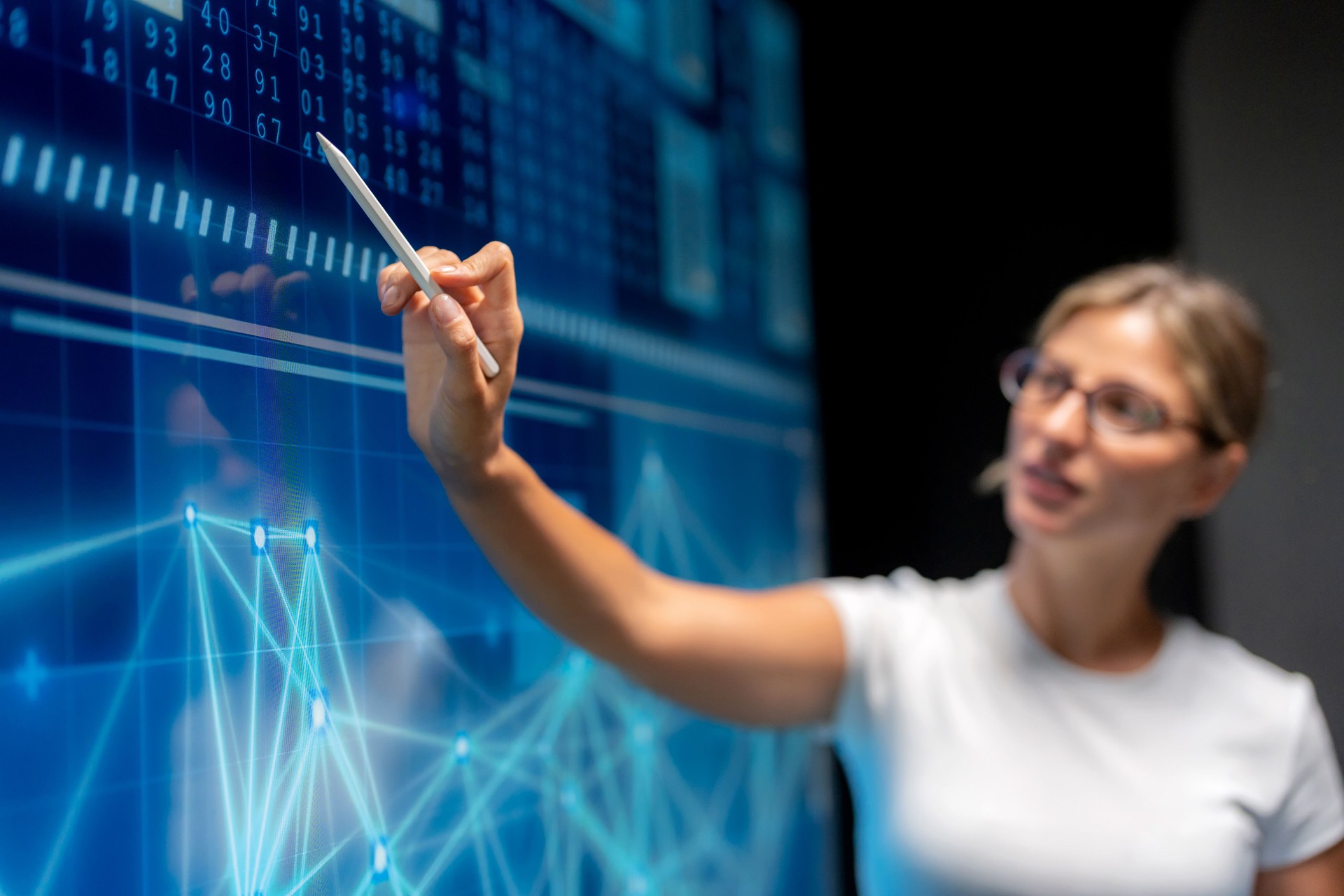 In a meeting room, a computer programmer shows executives a software solution for marketing and investment analysis. The corporate scene reflects cooperation, planning, big data, artificial intelligence, digital devices, and success in business innovation